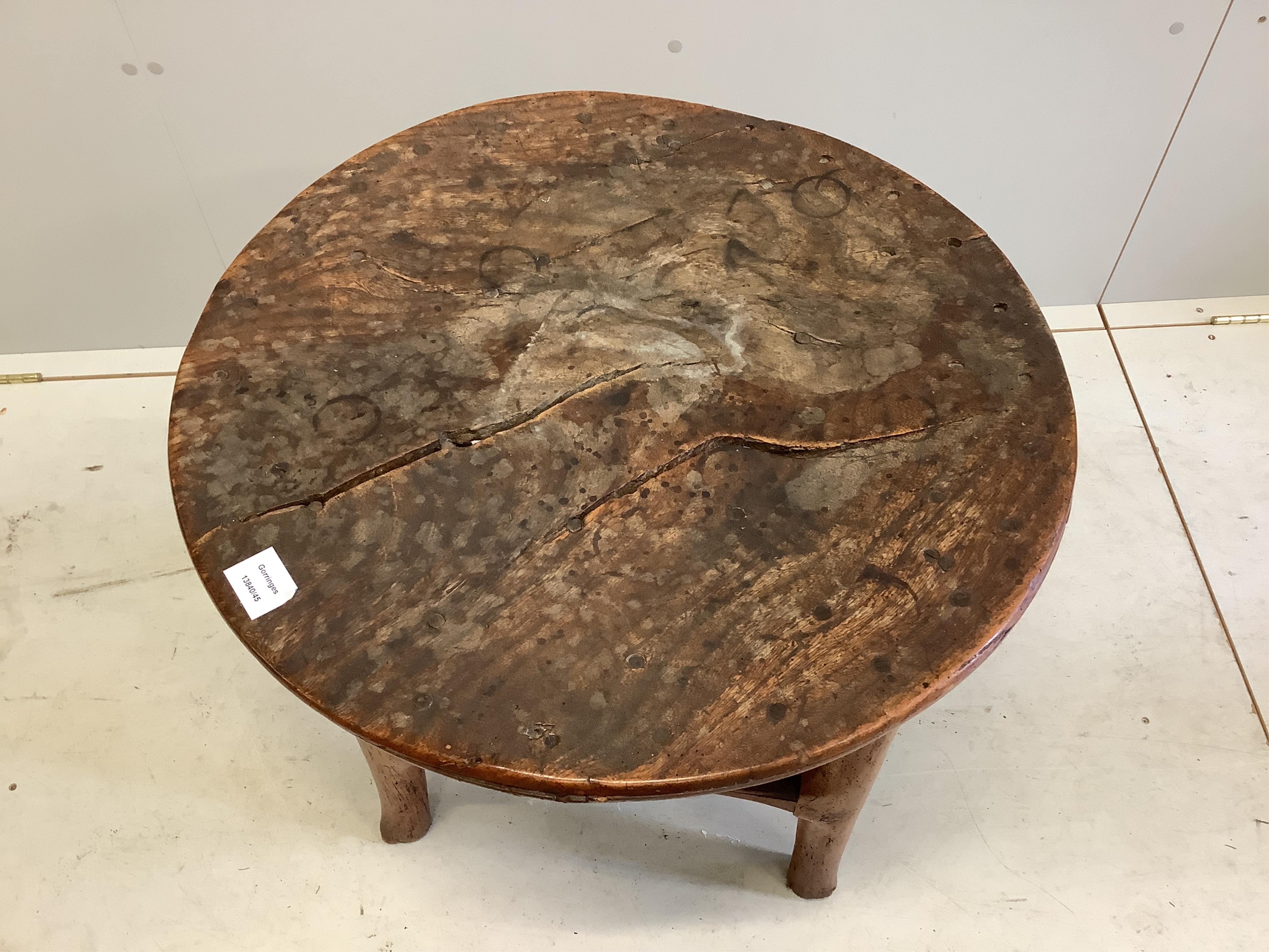 An 18th century elm cricket table, width 63cm, height 64cm. Condition - extensive splitting and old patches and repairs to the top, legs probably reduced but full of character